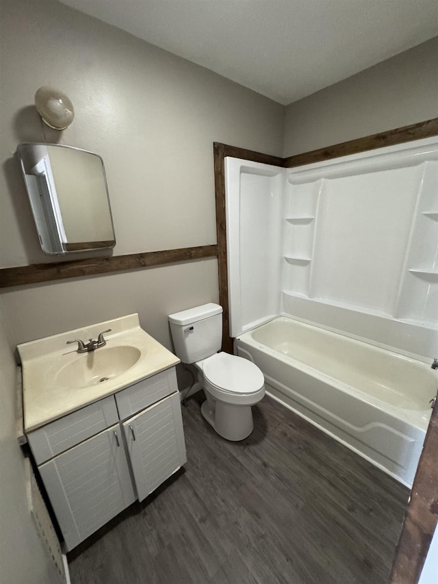  - bathroom with toilet, vanity, wood finished floors, and shower / washtub combination