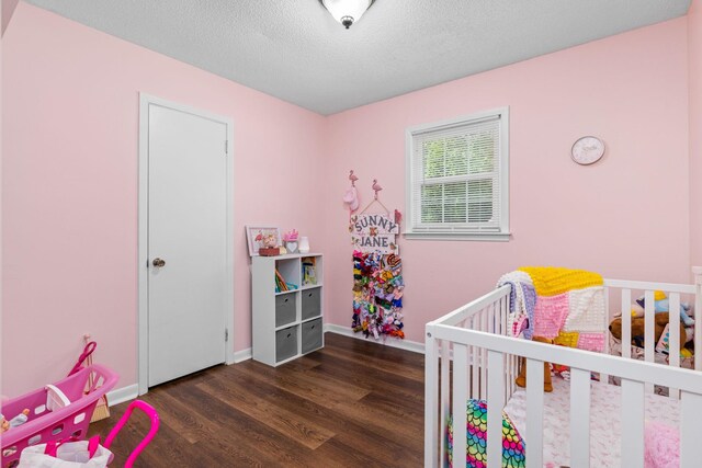  - bedroom with wood finished floors, a crib, and a textured ceiling
