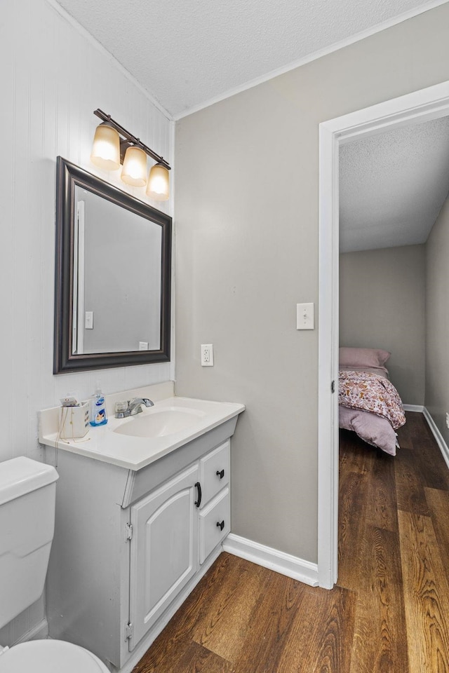  - bathroom featuring vanity, wood finished floors, ornamental molding, and a textured ceiling