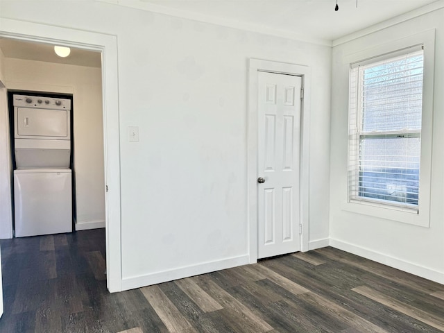 spare room featuring stacked washer and clothes dryer and dark wood-type flooring