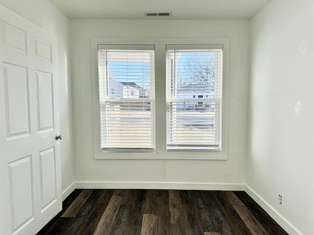 unfurnished room with a healthy amount of sunlight and dark wood-type flooring