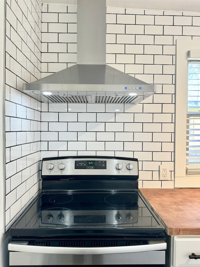 kitchen featuring electric range, backsplash, and ventilation hood