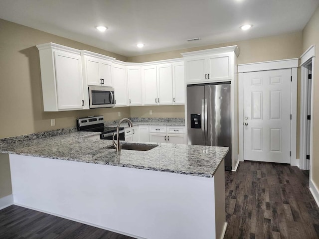 kitchen featuring sink, light stone counters, kitchen peninsula, white cabinets, and appliances with stainless steel finishes