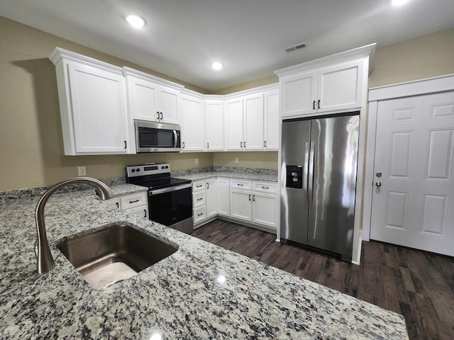 kitchen with white cabinetry, light stone countertops, sink, dark wood-type flooring, and appliances with stainless steel finishes