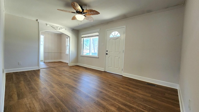 entrance foyer featuring visible vents, arched walkways, crown molding, ceiling fan, and dark wood-style flooring