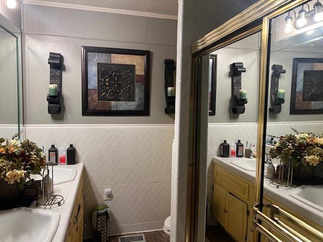 bathroom featuring vanity, crown molding, toilet, a textured ceiling, and tile walls