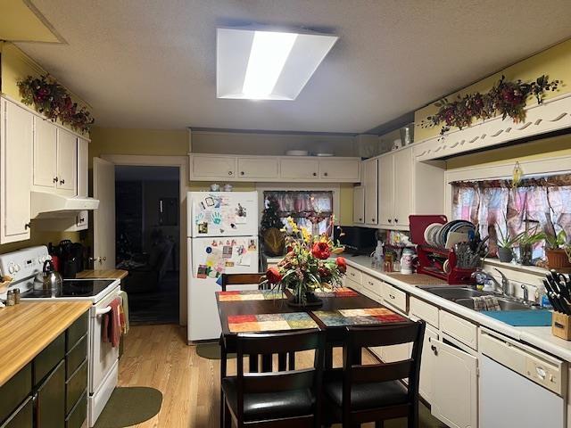 kitchen featuring a skylight, sink, light hardwood / wood-style floors, white appliances, and white cabinets