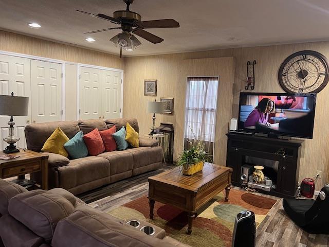 living room featuring hardwood / wood-style floors, ceiling fan, and wood walls