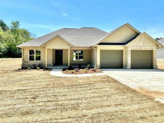 ranch-style home with a garage, roof with shingles, driveway, and brick siding