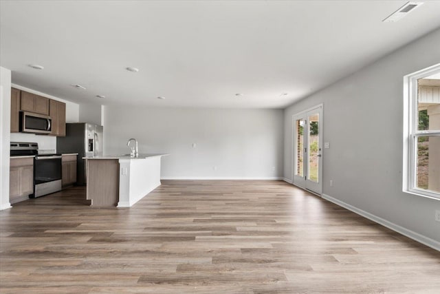  - unfurnished living room with light wood-style floors, baseboards, and a sink