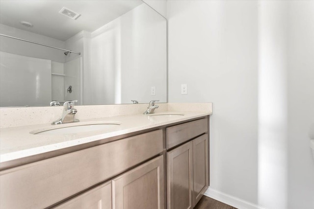  - full bath featuring double vanity, baseboards, and wood finished floors