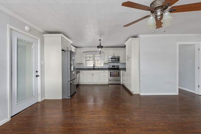 kitchen featuring dark countertops, crown molding, dark wood-style flooring, and stainless steel appliances