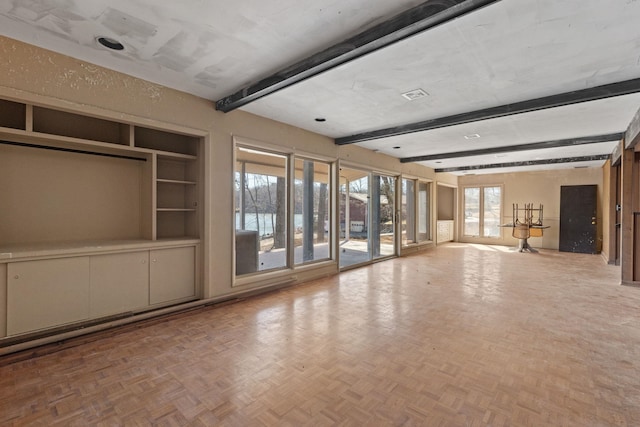 unfurnished living room featuring beamed ceiling and built in shelves