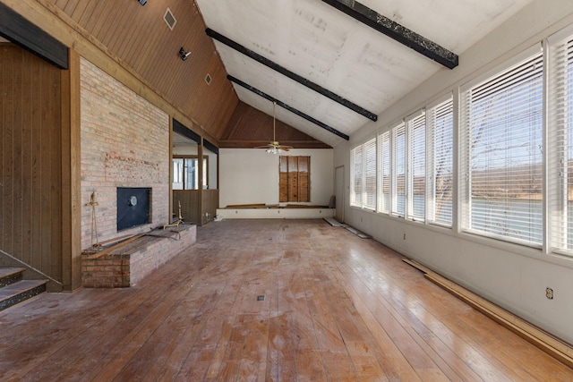 unfurnished living room featuring hardwood / wood-style floors, a ceiling fan, high vaulted ceiling, beam ceiling, and a brick fireplace