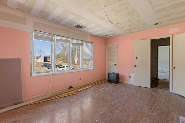 unfurnished room featuring visible vents, baseboards, and hardwood / wood-style floors