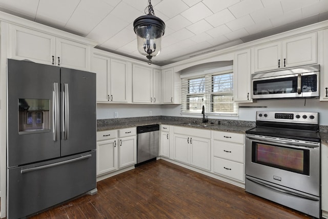 kitchen with a sink, decorative light fixtures, appliances with stainless steel finishes, white cabinets, and dark wood-style flooring