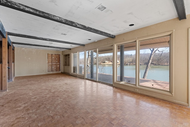 unfurnished room with beam ceiling, baseboards, a water view, and visible vents