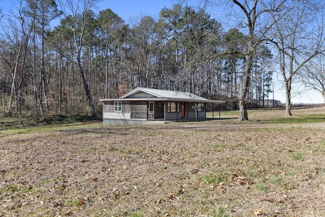 view of front facade featuring a view of trees and a sunroom