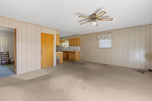 unfurnished living room featuring carpet floors and ceiling fan