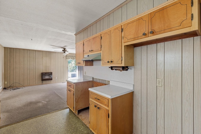 kitchen with wood walls, ceiling fan, a textured ceiling, light colored carpet, and heating unit