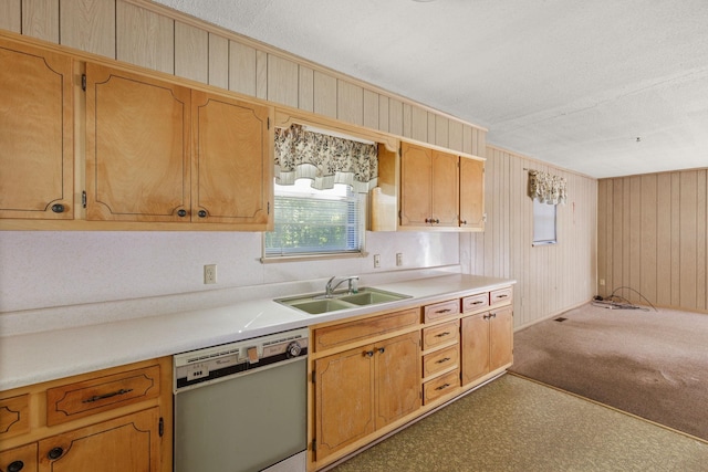 kitchen featuring sink, wooden walls, stainless steel dishwasher, carpet flooring, and a textured ceiling