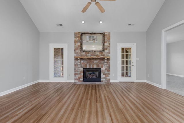 unfurnished living room with vaulted ceiling, light hardwood / wood-style flooring, a brick fireplace, and ceiling fan