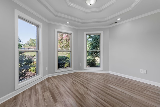 unfurnished room with hardwood / wood-style flooring, a raised ceiling, and crown molding