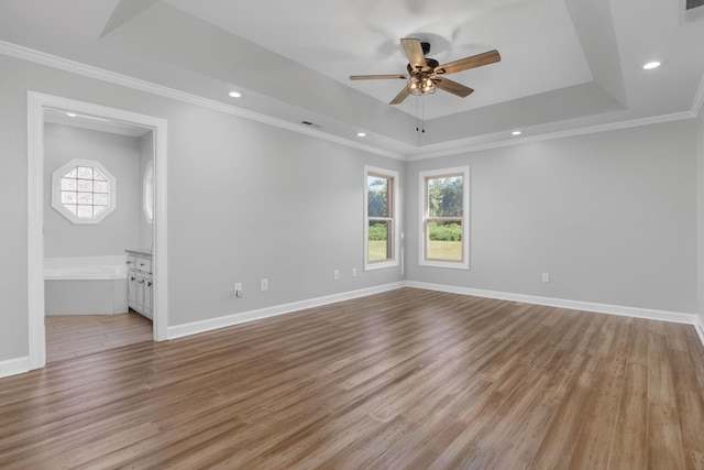 spare room featuring ceiling fan, a raised ceiling, ornamental molding, and light wood-type flooring