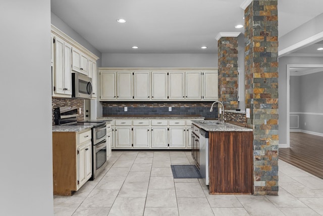 kitchen with cream cabinetry, decorative backsplash, sink, and appliances with stainless steel finishes