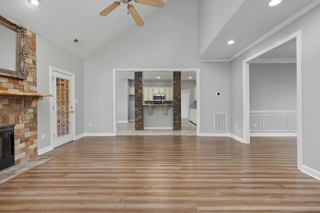 unfurnished living room featuring ornamental molding, ceiling fan, light hardwood / wood-style flooring, a fireplace, and lofted ceiling