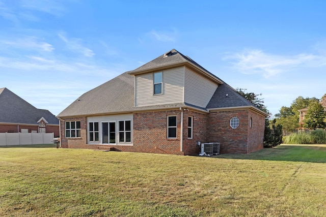 rear view of house featuring cooling unit and a yard