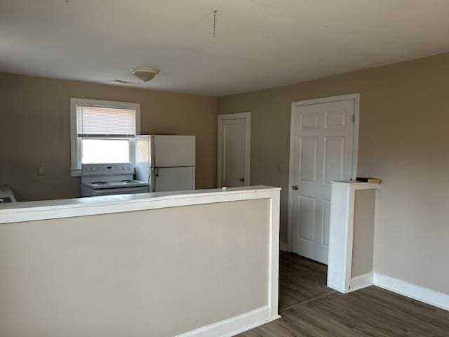 kitchen with dark hardwood / wood-style floors, white appliances, and kitchen peninsula