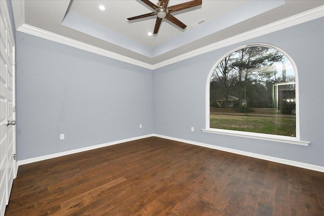 empty room with a tray ceiling, ceiling fan, and dark hardwood / wood-style flooring