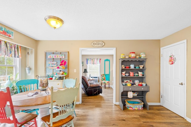  - dining room featuring wood finished floors, baseboards, and a textured ceiling