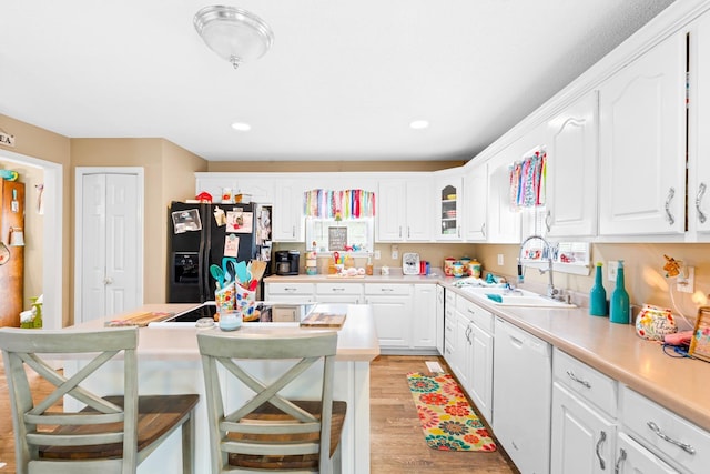  - kitchen with black appliances, a sink, light wood finished floors, white cabinets, and a kitchen breakfast bar