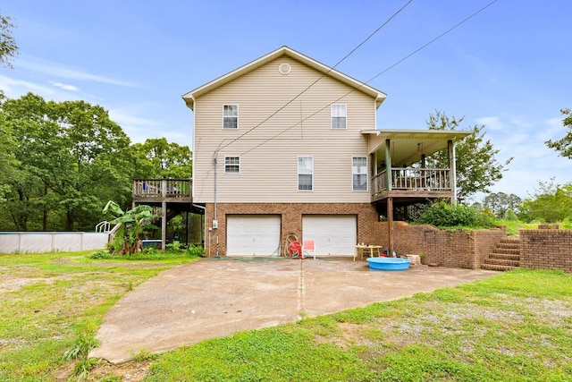  - back of house with an attached garage, driveway, a wooden deck, and brick siding