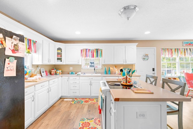  - kitchen with freestanding refrigerator, a breakfast bar, light wood finished floors, white electric range, and a sink