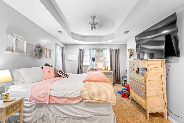  - bedroom with light colored carpet, a ceiling fan, and a raised ceiling