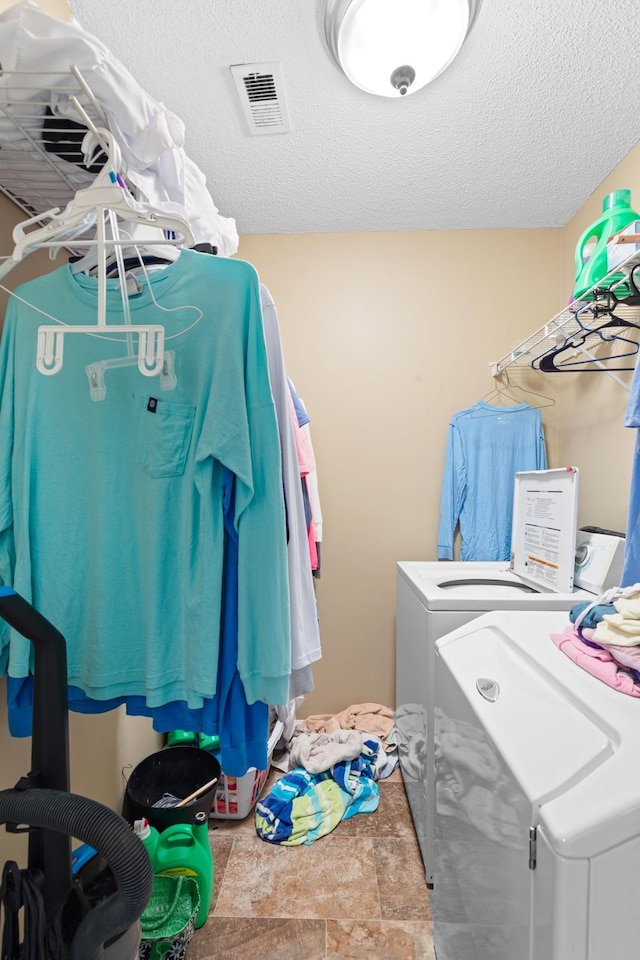  - laundry room featuring separate washer and dryer, stone finish flooring, and a textured ceiling