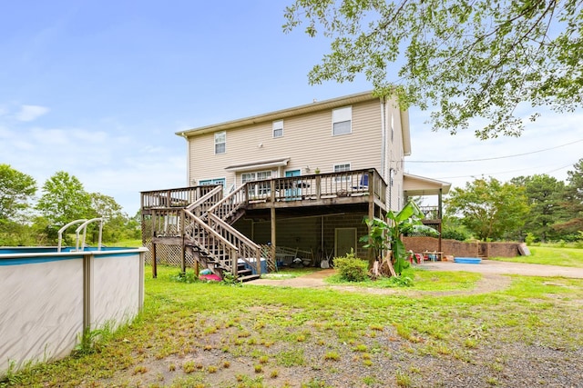 - back of house with a deck, an outdoor pool, stairs, and a lawn