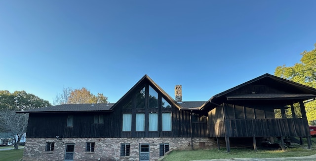  - rear view of property featuring a yard, brick siding, a chimney, and a sunroom