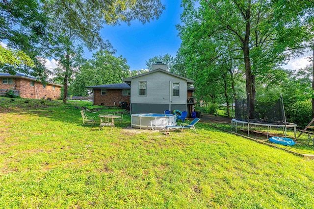  - view of green lawn featuring a trampoline and an outdoor pool
