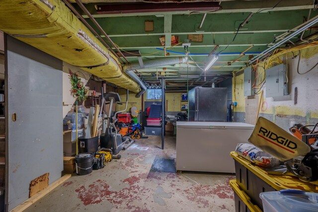  - unfinished below grade area with electric panel, fridge, and freestanding refrigerator