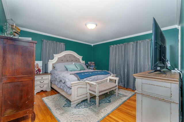  - bedroom with crown molding and wood finished floors