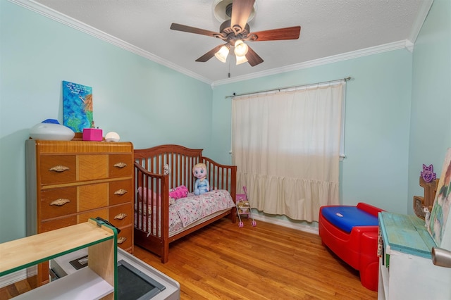  - bedroom featuring crown molding, wood finished floors, a nursery area, and a ceiling fan
