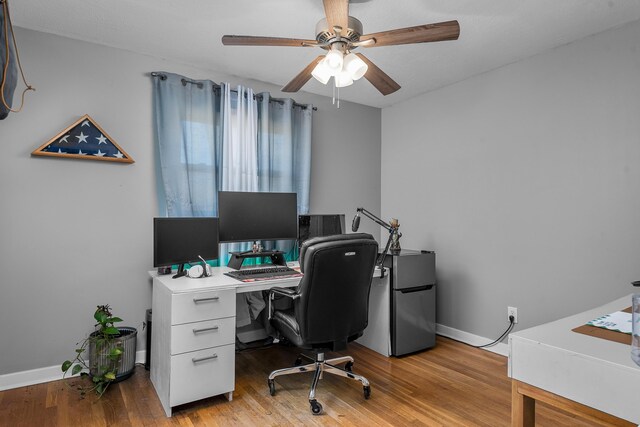 home office with light wood-style floors, ceiling fan, and baseboards