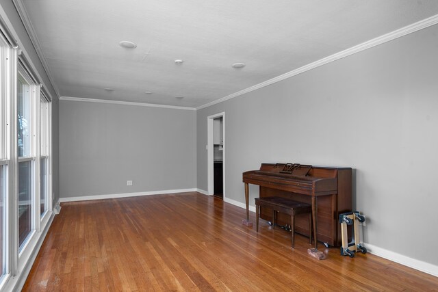 spare room with ornamental molding, baseboards, and wood finished floors