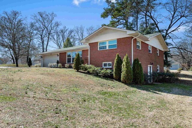 tri-level home with a garage, brick siding, and a front yard