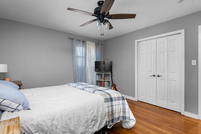 bedroom with a ceiling fan, a closet, baseboards, and wood finished floors