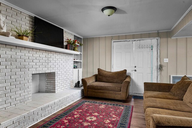 living area featuring ornamental molding, a brick fireplace, wood finished floors, and visible vents